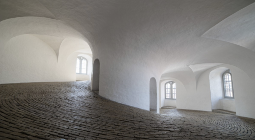 Daylight coming in through arched windows and reflecting off white, curved walls