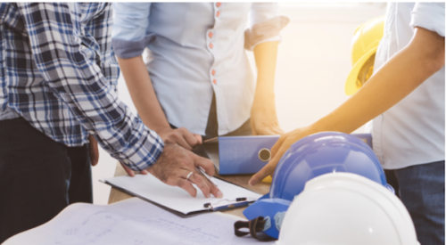 Group of construction workers and architects looking at building plans