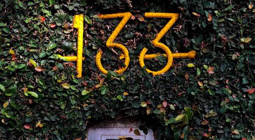 Wall covered in plant with mail slot and address numbers