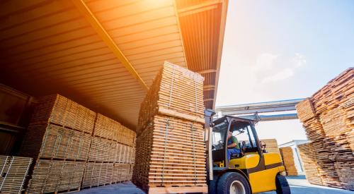 Lumber is carried through a warehouse.