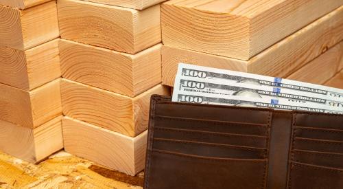 Stack of lumber next to wallet full of hundred dollar bills