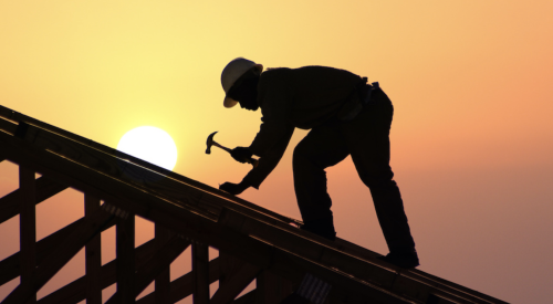 Man using hammer building home roof at dawn