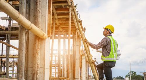 man wearing hardhat climbing ladder to inspect new construction