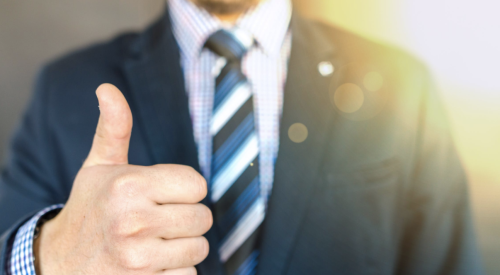 man in blue suit giving a thumbs up