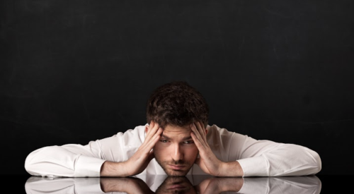 Man with head on desk stressing over sales