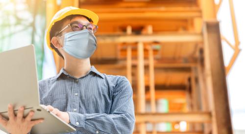 Man wearing hard hat and protective face mask at construction site