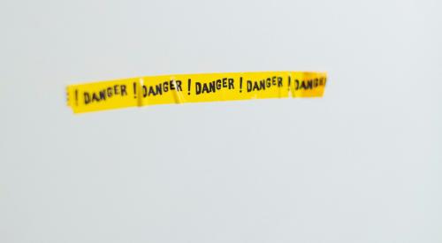 Danger yellow tape on grey wall