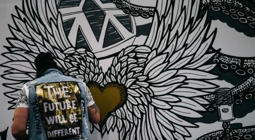 Man in front of mural with jean jacket on