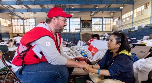 Relief worker holding the hand of a Maui native affected by the wildfires