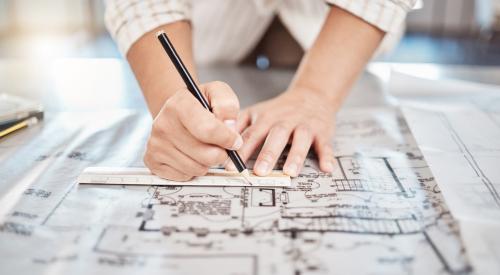 Person measuring and marking up paper floor plans