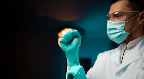 healthcare worker wearing protective face mask putting on latex gloves