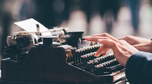 Person using a typewriter on a desk outside