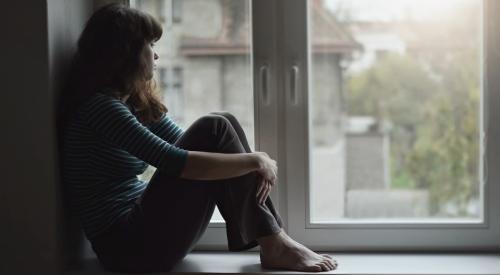 Young woman looking sad while gazing out of window