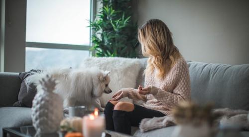 Millennial woman at home sitting on the couch with her dog