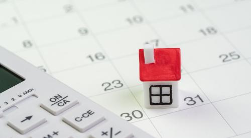 Small house and calculator on monthly calendar