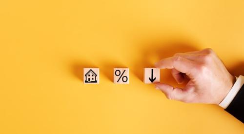 Wooden blocks with house, percentage point, and downward arrow against yellow background