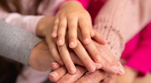 Grandmother's hands covered by younger generations' hands