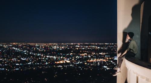 Young person sitting on ledge over cityscape