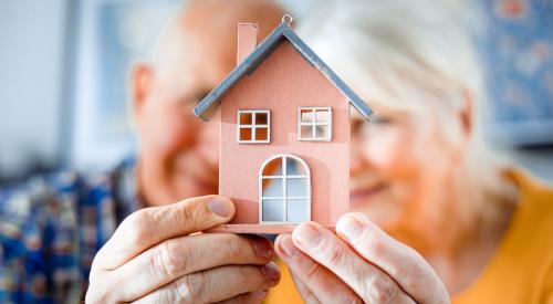 Old couple holding small house model