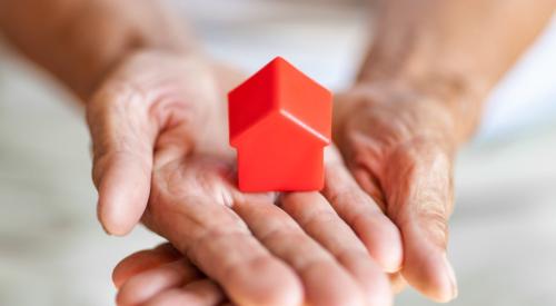 Old woman holding red house model