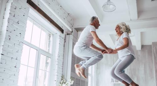 Older couple jumping on bed in apartment