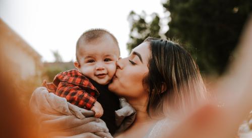 Woman holding up and kissing her child