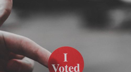 White hand with red sticker on finger that says 'i voted'