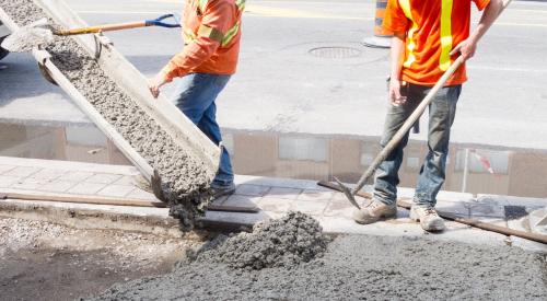 Construction workers in reflective vests pouring concrete