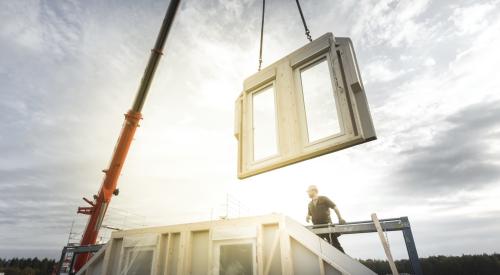 Crane lowering prefab wall panel into place in the jobsite