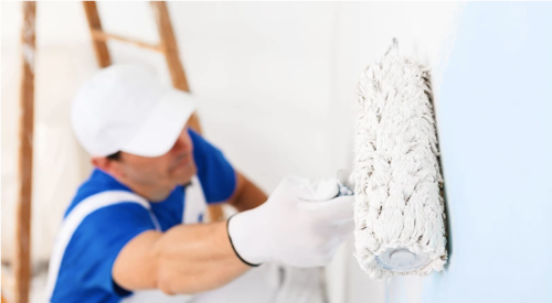 Professional painter using roller to paint wall