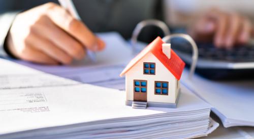 Person calculating taxes in front of small home model