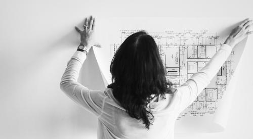 Woman hanging up floorplans on wall