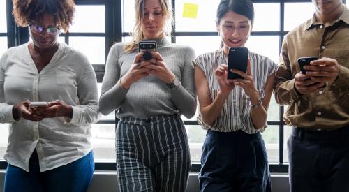 Millennials using smartphones by a window