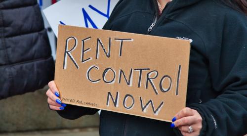 Person protesting with rent control sign