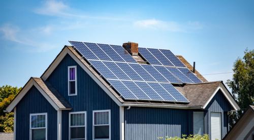 Blue house with solar panels on the roof is more energy efficient