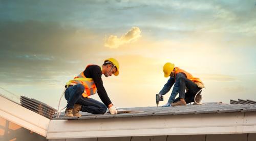 Roofers installing shingles on house roof