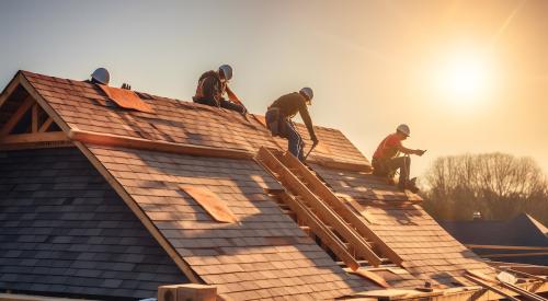 Roofers installing shingles on new single-family house