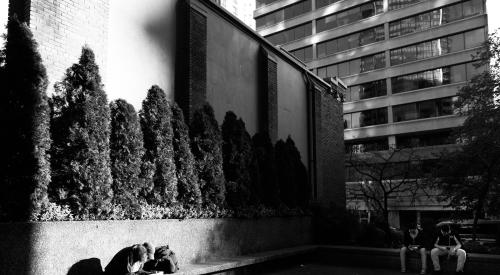 Three people on benches in city in b/w photo