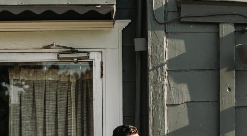 Millennial standing outside of storefront, looking happy