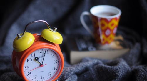 Clock and coffee mug on a bed