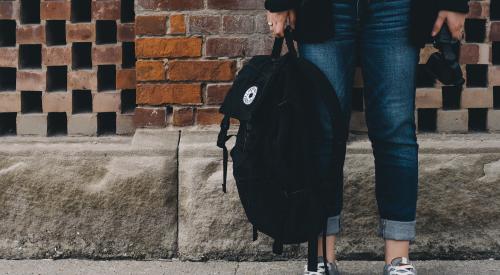 Person with backpack on sidewalk