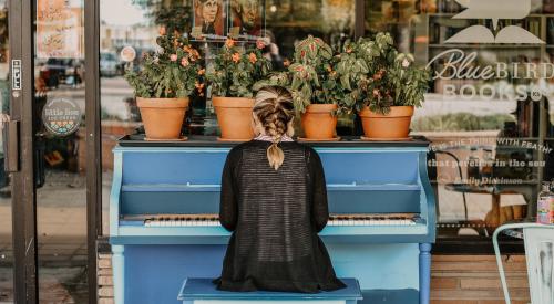 Woman playing piano outside Bluebird Bookstore in Hutchinson, Kan