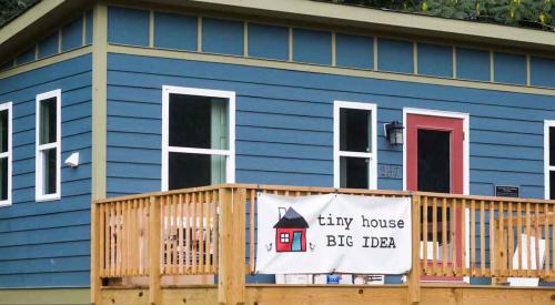 Small blue house with tiny house banner out front