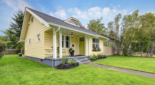 Small yellow house surrounded by green lawn