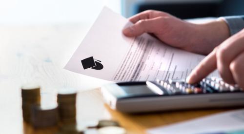 Person holding paper with student loan information while typing on calculator