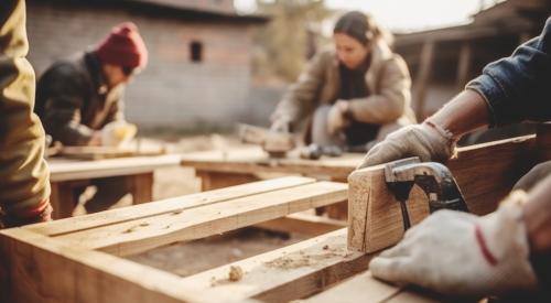 Group of volunteers building house frame