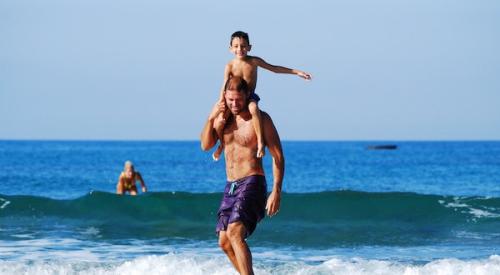 Boy_on_shoulder_of_man_surfing