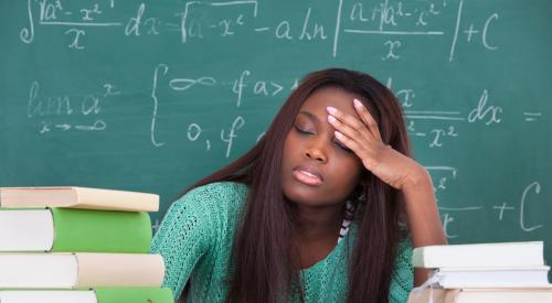 overworked teacher sitting at her desk