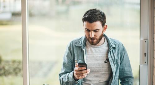 Man using smartphone by a window