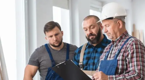 three workers review COVID-19 precautions on the construction jobsite